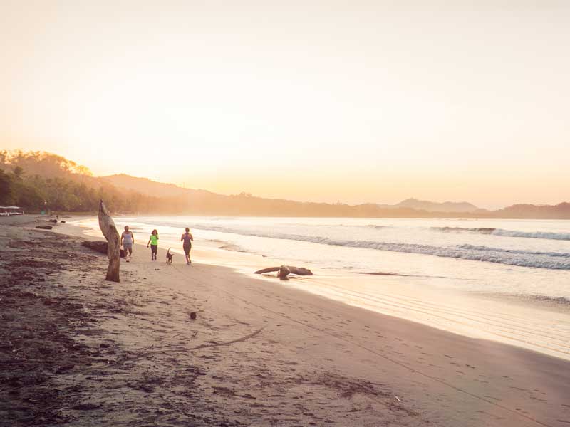 Un grupo de personas de pie en lo alto de una playa de arena.