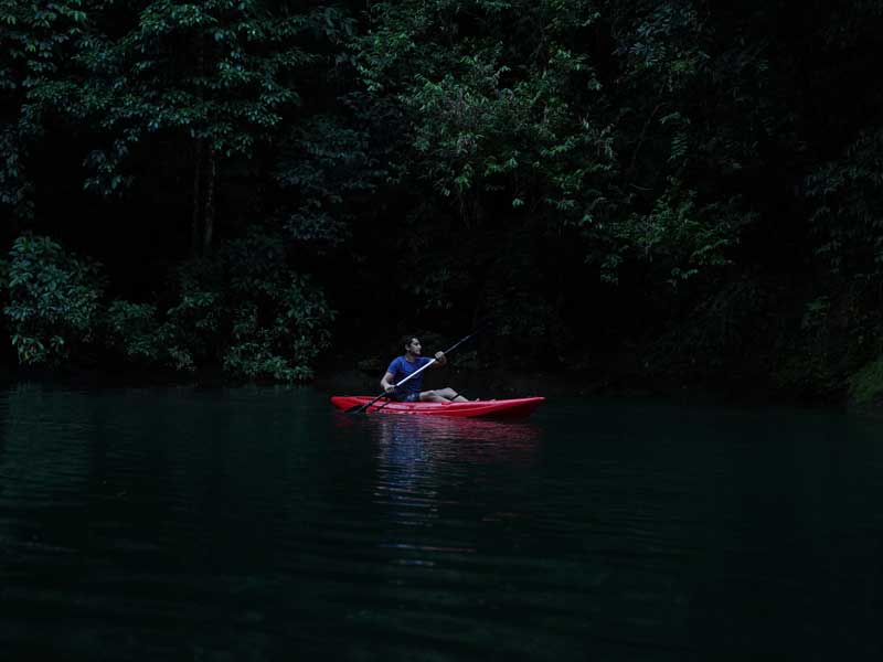 Un hombre en un kayak rojo rema por el agua.