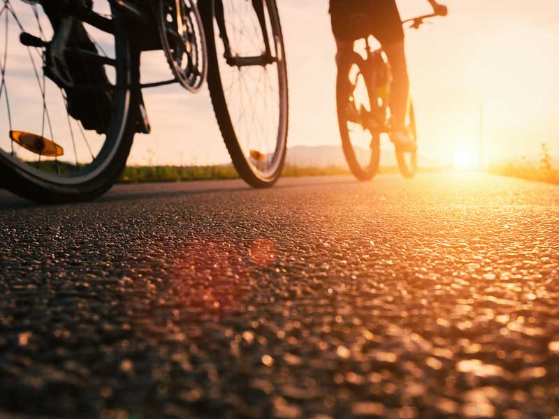 Una persona en bicicleta por una calle al atardecer.