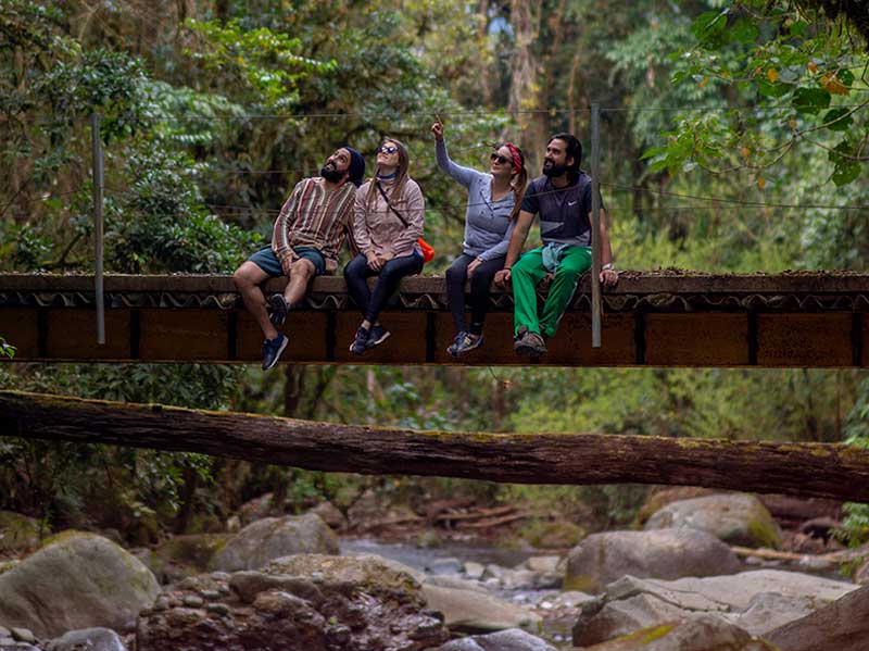 Un grupo de personas sentadas en un puente sobre un río.