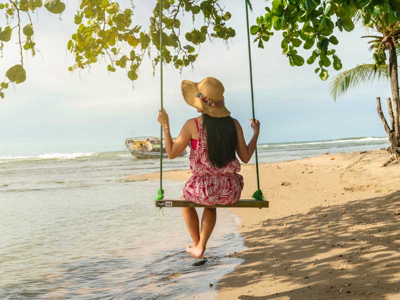 Una mujer sentada en un columpio en la playa.