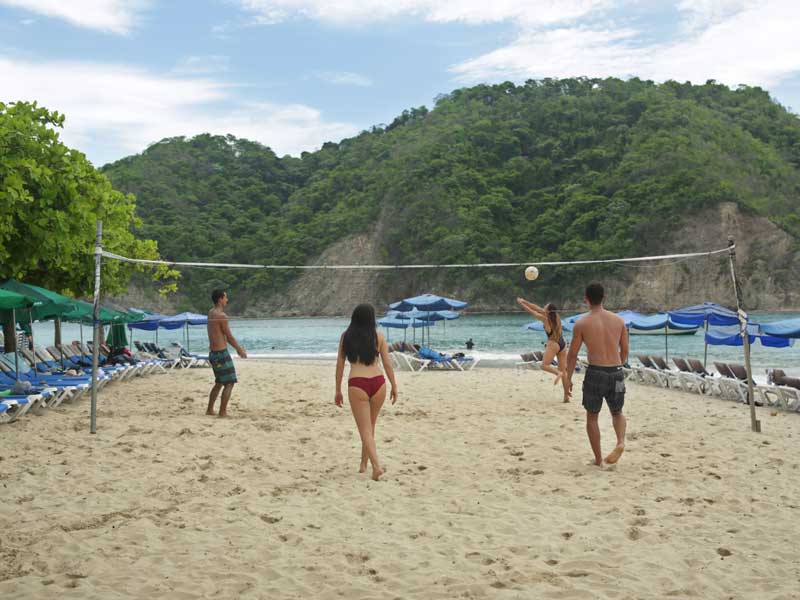Un grupo de personas jugando al voleibol en una playa.