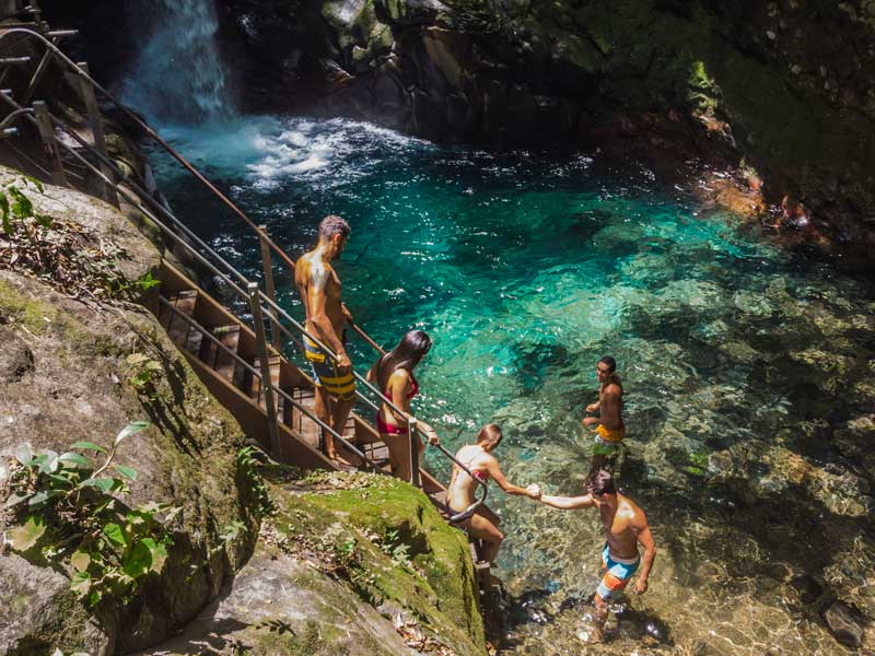 Un grupo de personas en lo alto de un acantilado junto a una cascada.
