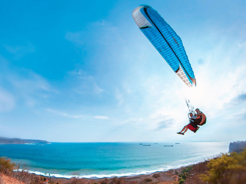 Un hombre vuela por los aires montado en una tabla de kitesurf