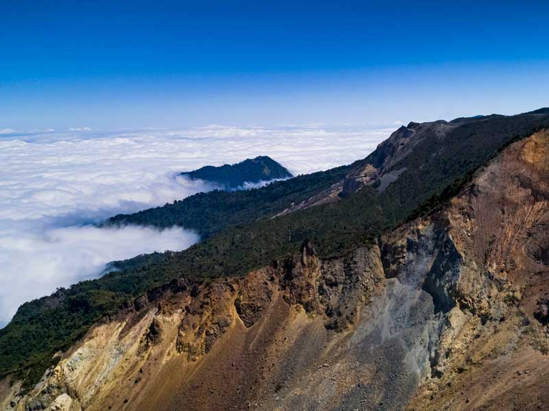 Vista de la cima de una montaña con nubes debajo.