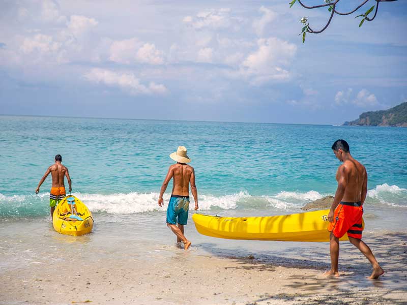 Un grupo de personas en una playa con una tabla de surf amarilla.