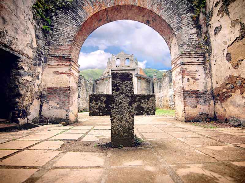 Una cruz de piedra en medio de un patio.