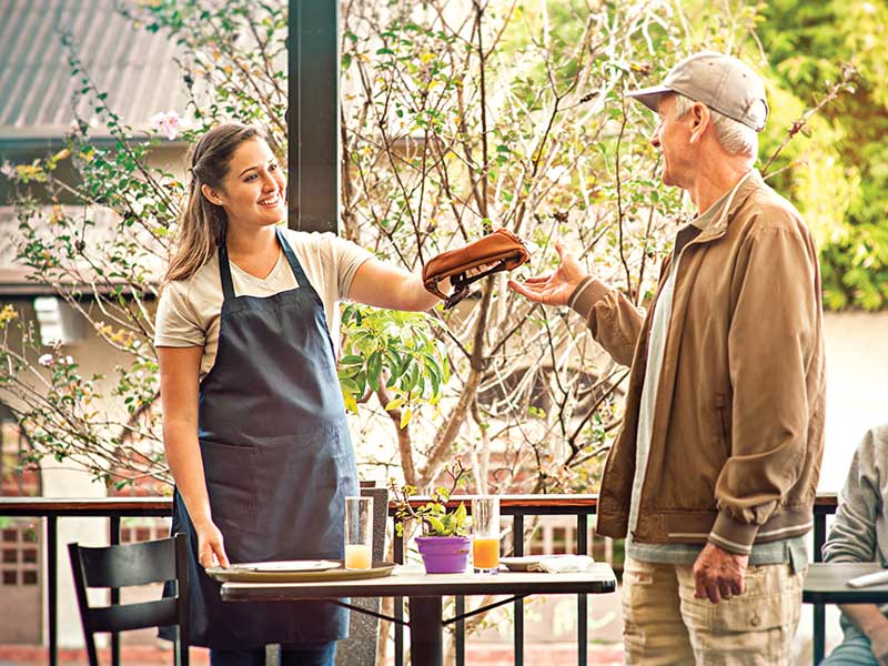 Un hombre entrega una bandeja de comida a una mujer.