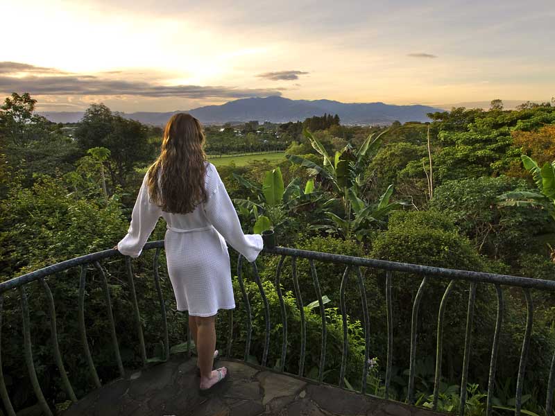 Una mujer en un balcón con vistas a un exuberante valle verde.