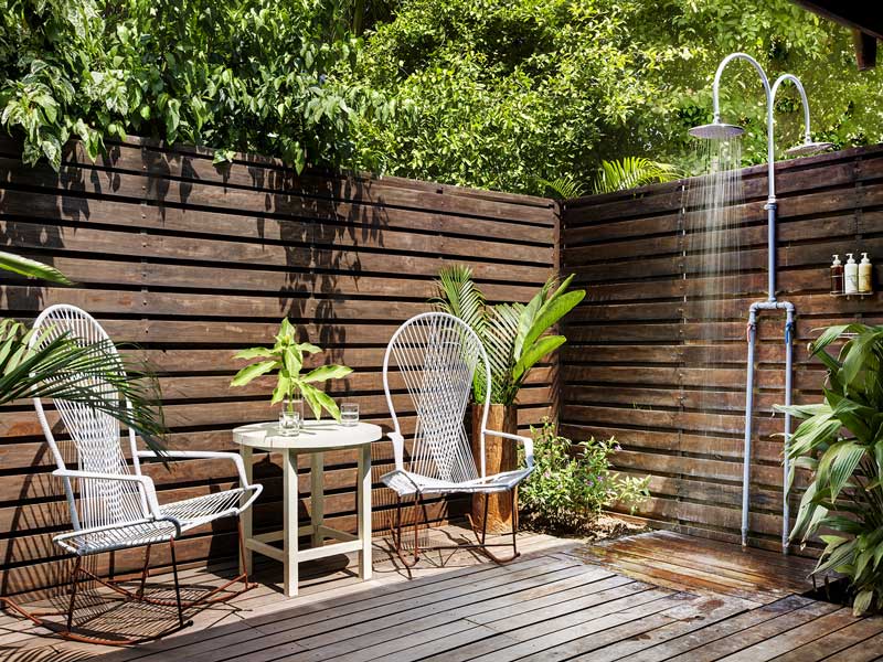 Una terraza de madera con dos sillas y una mesa.