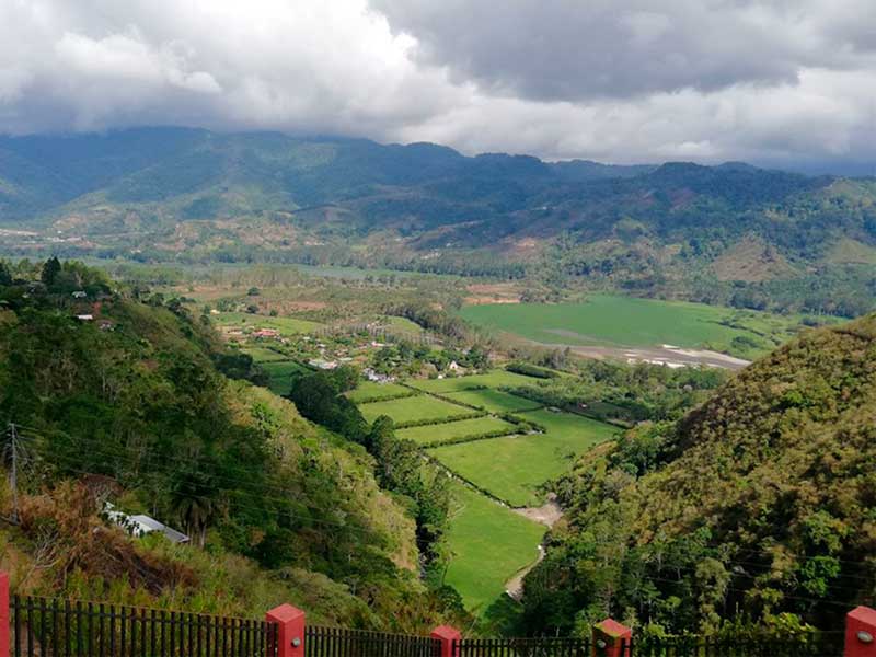 Un exuberante valle verde rodeado de montañas bajo un cielo nublado.