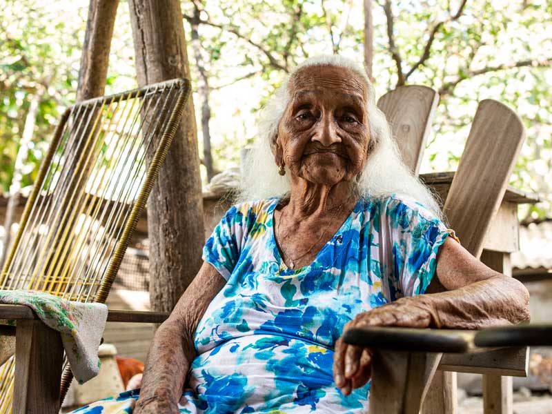 Una anciana sentada en una silla al aire libre.