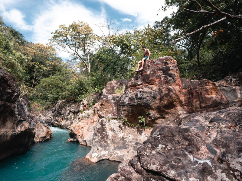 Una persona sentada en una roca sobre un río.