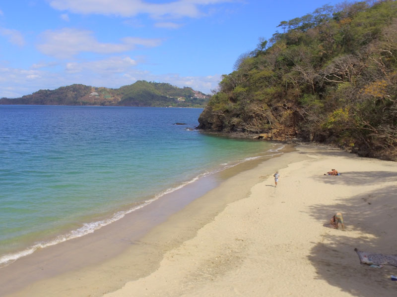 Una playa de arena con poca gente.
