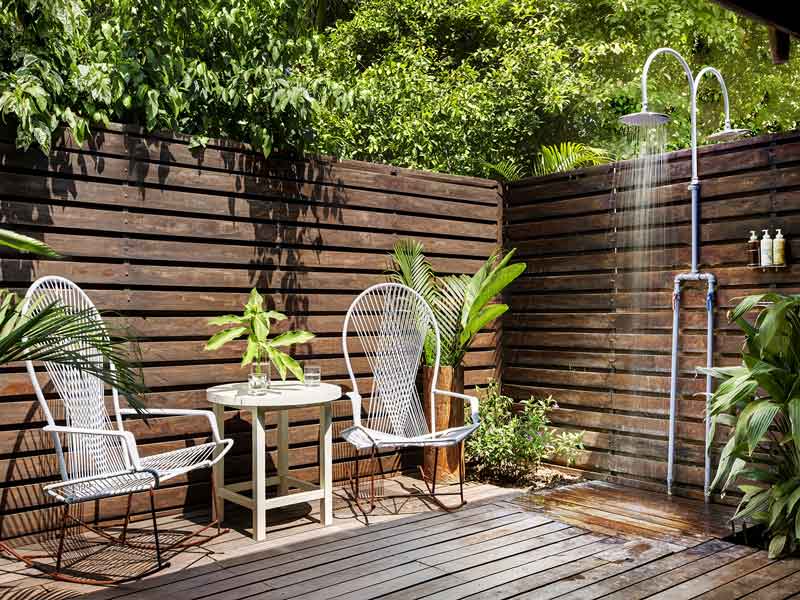 Una terraza de madera con dos sillas y una mesa.