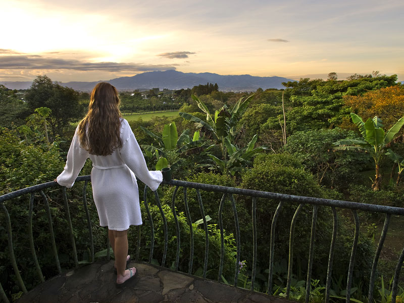 Una mujer en un balcón con vistas a un exuberante valle verde.