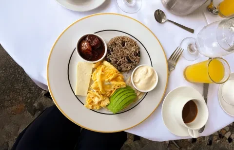 un plato con el desayuno sobre una mesa, acompañado de café y zumo de naranja
