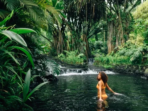 mujer caminando en un manantial en la selva
