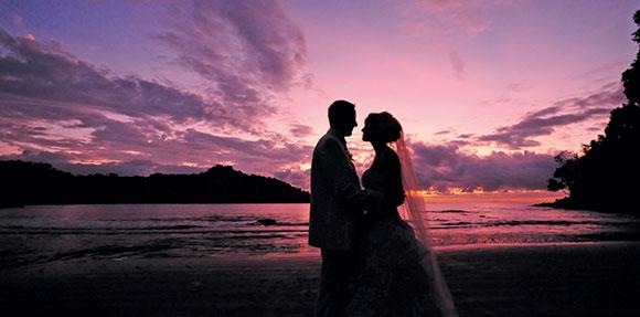 Novia y novio en la playa al atardecer