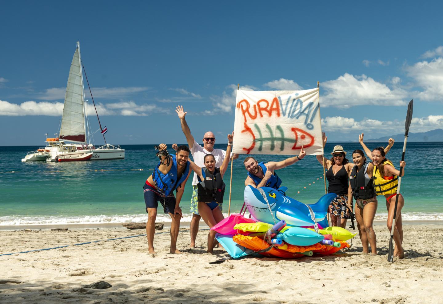 Gente en la playa con un cartel pura vida